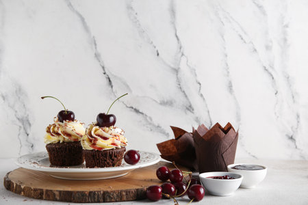 Plate with sweet cherry cupcakes and bowls of jam on white backgroundの写真素材
