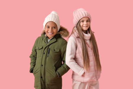 Cute little happy children in winter clothes on pink backgroundの写真素材