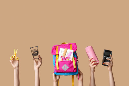 Female hands with backpack, different school supplies, shopping cart and payment terminal on beige background, closeupの写真素材