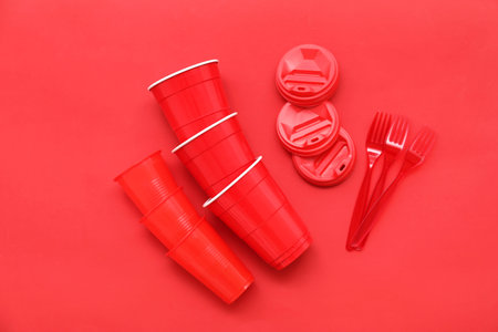 Set of plastic tableware on red background