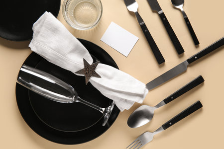 Beautiful table setting with black plates on beige backgroundの写真素材
