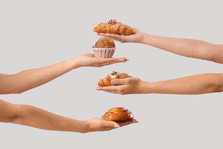 Female hands with different tasty pastry on gray backgroundの写真素材