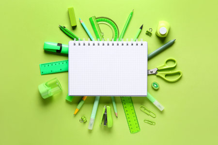 School supplies with open notebook on green background. Top view