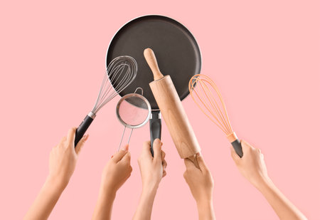 Female hands with different baking utensils on pink backgroundの写真素材