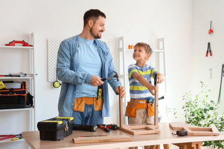 Happy father and his little son with different instruments assembling furniture at homeの写真素材