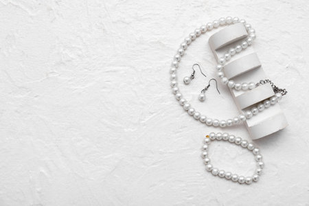Set of stylish jewelery with pearls on white grunge backgroundの写真素材