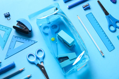 Pencil case with different stationery on blue background. Top viewの写真素材