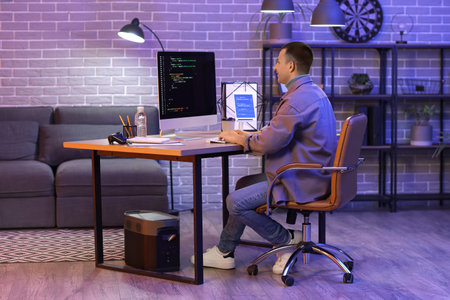 Male programmer working with computer in office at night