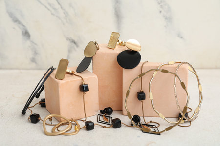 Stylish jewelery and plaster stands on white table near marble wall