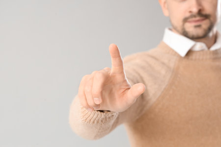 Young businessman using virtual screen on light background, closeupの写真素材