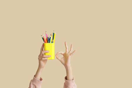 Child with pencils on beige backgroundの写真素材