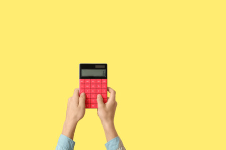 Child with calculator on yellow backgroundの写真素材