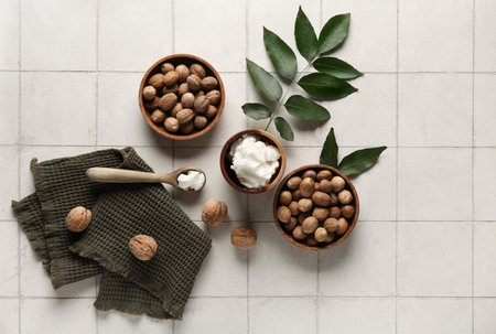 Bowls and spoon of shea butter with nuts on white tile backgroundの写真素材