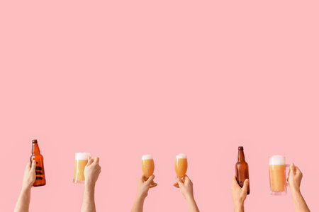 Many hands holding glasses of beer and bottles on pink backgroundの写真素材