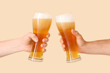 Hands holding beer glasses on beige backgroundの写真素材