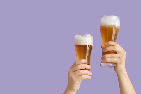 Hands holding beer glasses on lilac backgroundの写真素材