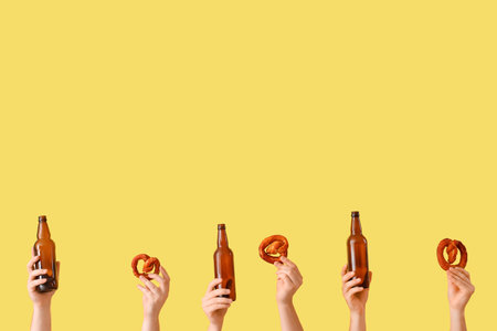 Many hands holding beer glasses and pretzels on yellow backgroundの写真素材