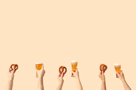Many hands holding glasses of beer and pretzels on beige backgroundの写真素材