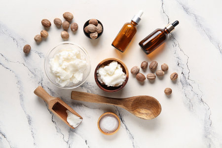 Bowls of shea butter with bottles of cosmetic oil and nuts on white backgroundの写真素材