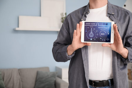 Young man with smart home security system control panel in bedroom, closeup