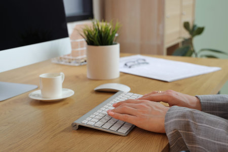 Female hands typing on keyboard at workplace with modern computer in beautiful office