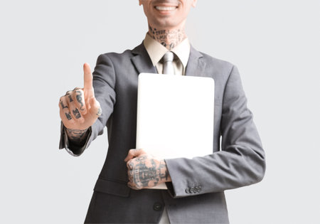 Young businessman with laptop using virtual screen on light background, closeupの写真素材