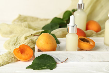 Bottles of cosmetic oil with fresh apricots on white wooden backgroundの写真素材
