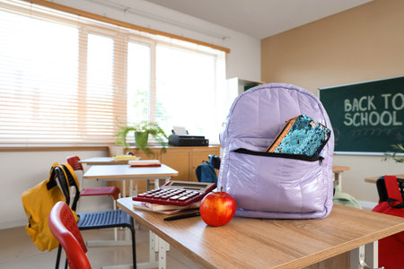 Lilac backpack with pencil case and apple on desk in classroomの写真素材