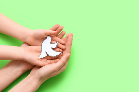 Child's and female hands with paper dove on green background. International Day of Peaceの写真素材