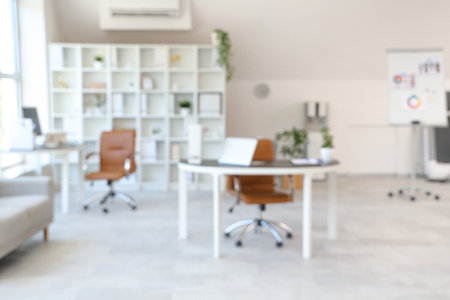 Interior of light open space office with workplaces, shelving unit and armchairs, blurred viewの写真素材