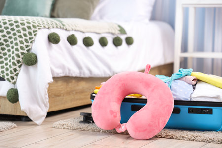 Packed suitcase with neck pillow and belongings on floor in bedroom. Travel conceptの写真素材