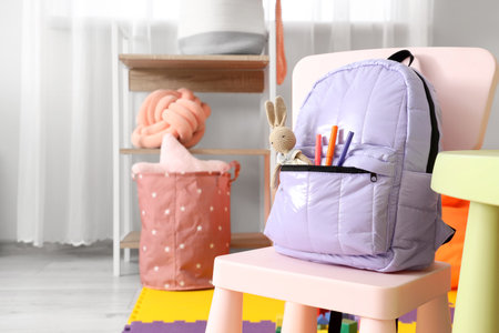 Lilac backpack with toy bunny on chair in children's room, closeupの写真素材