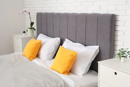 Comfortable bed and bedside tables with orchid in bedroomの写真素材