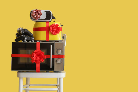 Different appliances with gift bows on chair against yellow backgroundの写真素材
