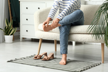 Young woman suffering from joint pain after heeled sandals at homeの写真素材