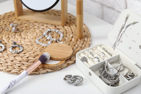 Box with different stylish jewelry, powder and makeup brush on table, closeupの写真素材