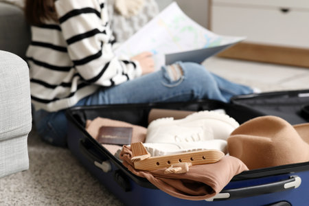 Young woman learning map near suitcase on floor at home, closeup. Travel conceptの写真素材