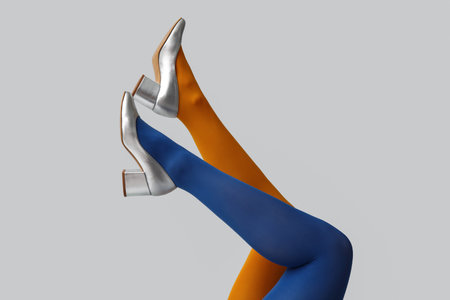 Legs of young woman in colorful tights and silver shoes on white backgroundの写真素材