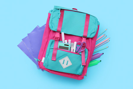 Pink school backpack with stationery on blue background
