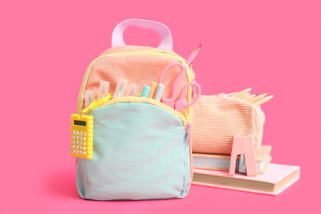 Blue school backpack with stationery and books on pink backgroundの写真素材