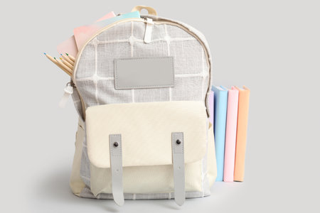 Gray school backpack with stationery and books on white backgroundの写真素材