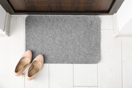 Gray door mat near doorway on white floor in hallwayの写真素材