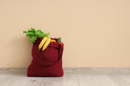 Red shopper bag with fruits and vegetables on beige backgroundの写真素材