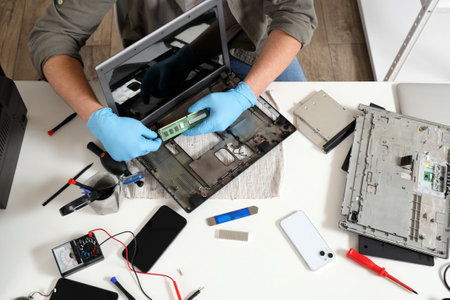 Male technician repairing laptop at table in service center, top viewの写真素材