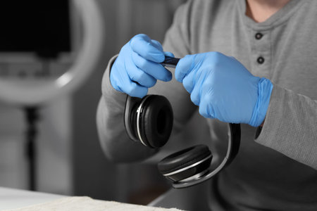 Male technician repairing headphones at table in service center, closeup