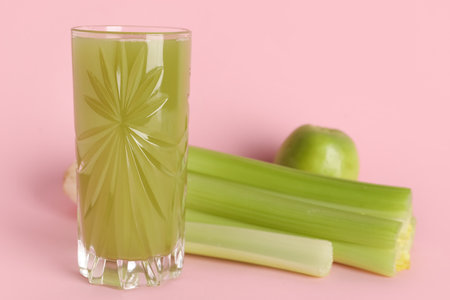 Glass of fresh juice with celery and apple on pink background, closeupの写真素材