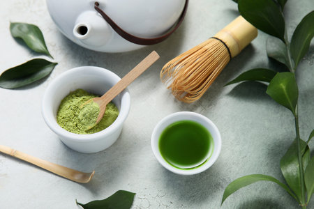 Bowls of matcha tea and powder with chasen on grunge background