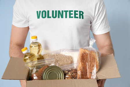 Male volunteer with food donations on blue background, closeupの写真素材