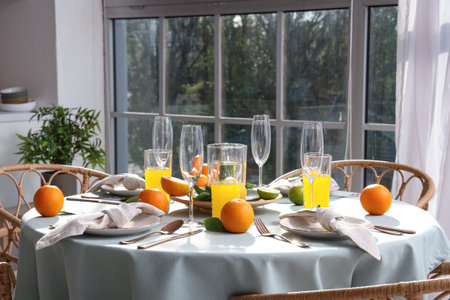 Beautiful table setting with citrus fruits and orange juice in living room