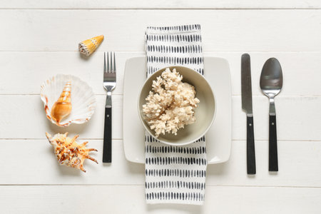 Beautiful table setting with seashells and coral on white wooden backgroundの写真素材